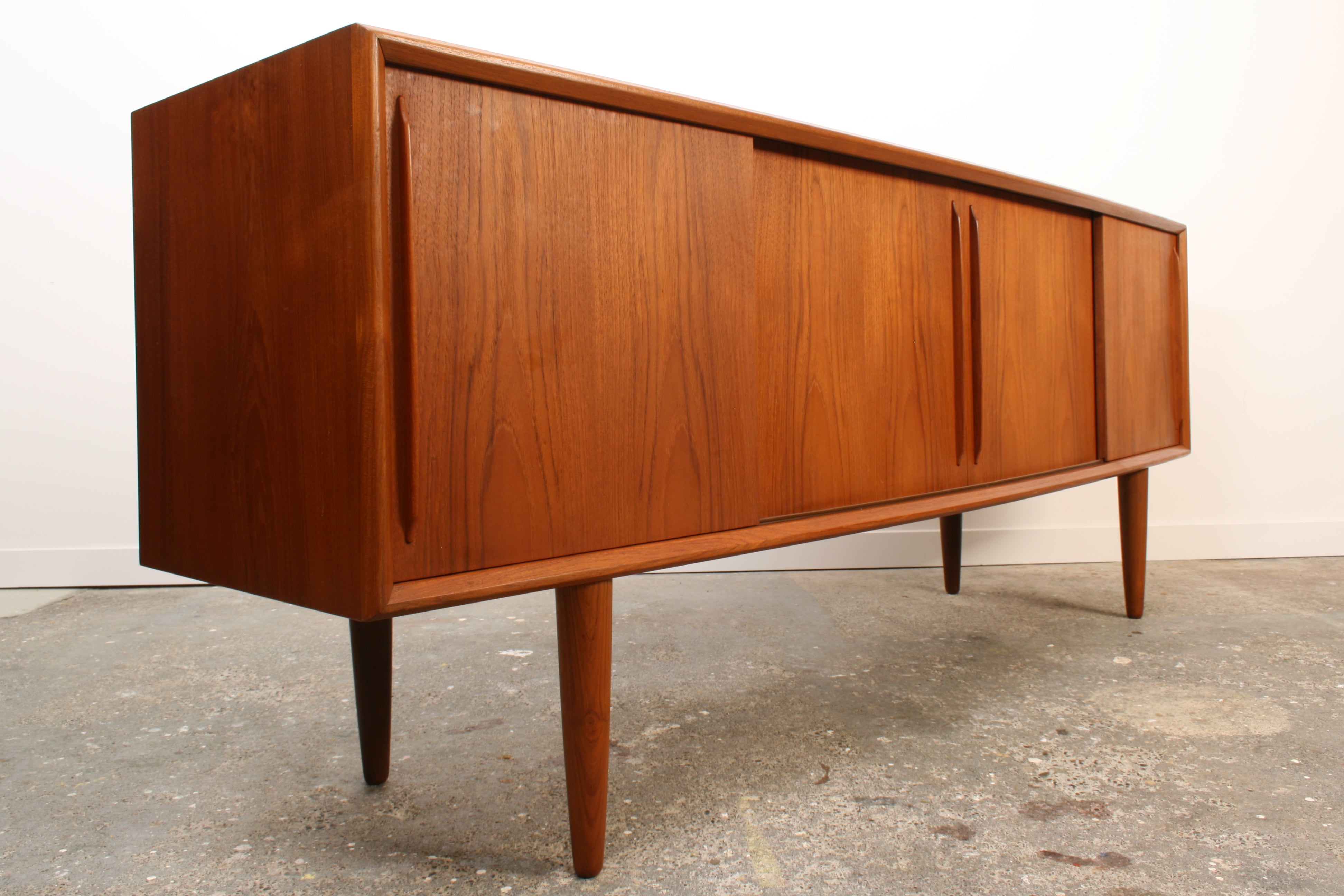 Danish Teak sideboard by H P Hansen. Shown at a slight angle from the left. It has four sliding doors which are closed.